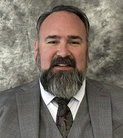 Man with beard wearing a grey, 3-piece suit